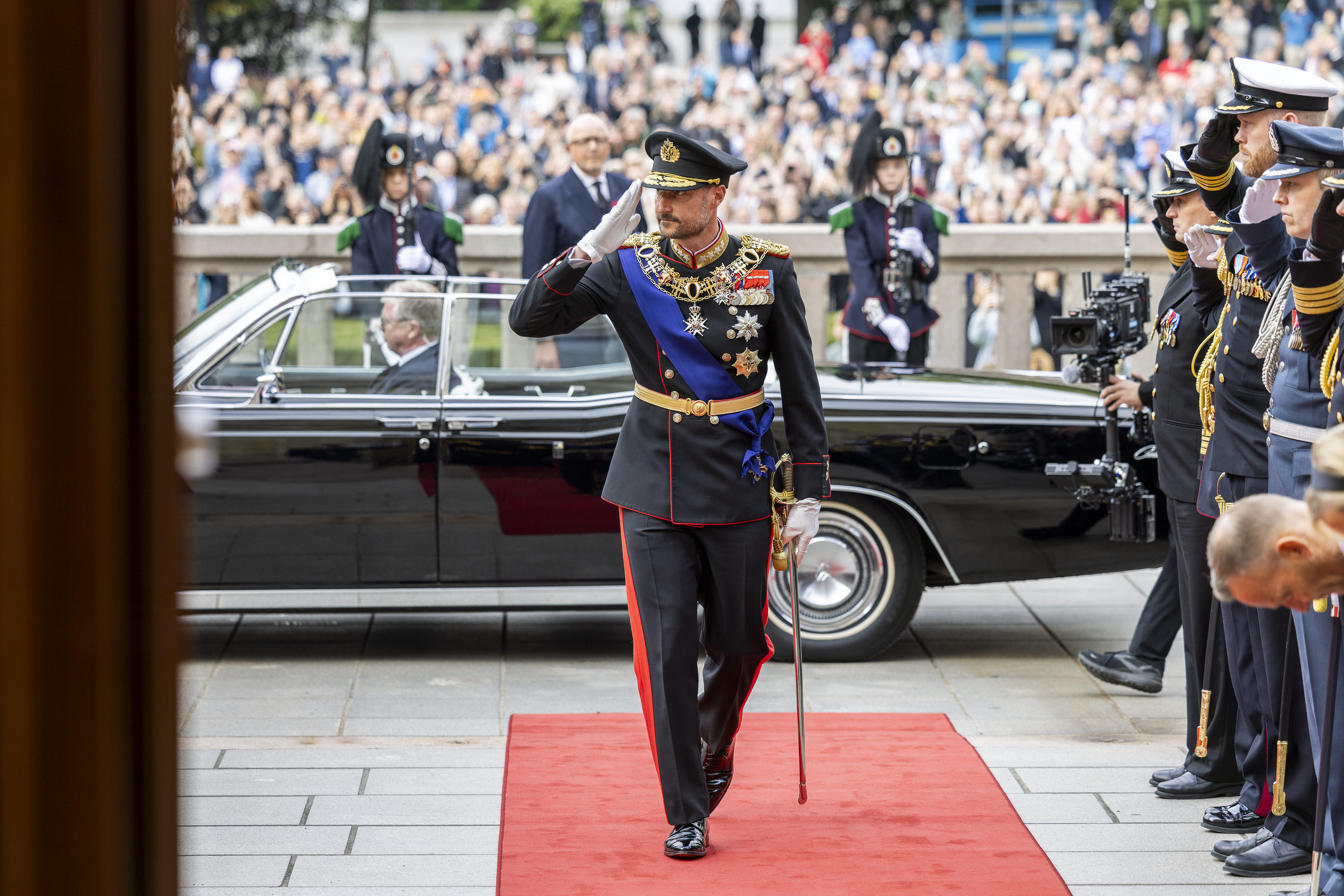 kong Haakon på vei inn i Stortinget. Han hilser til luen.