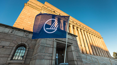 Finske riksdagen med Nordisk Råds flagg i forgrunnen.