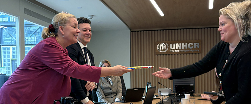 Delegasjonsleder Silje Hjemdal overrekker en melkesjokolade til assisterende høykommissær Kelly Clements og direktør for Europakontoret Philippe Leclerk.