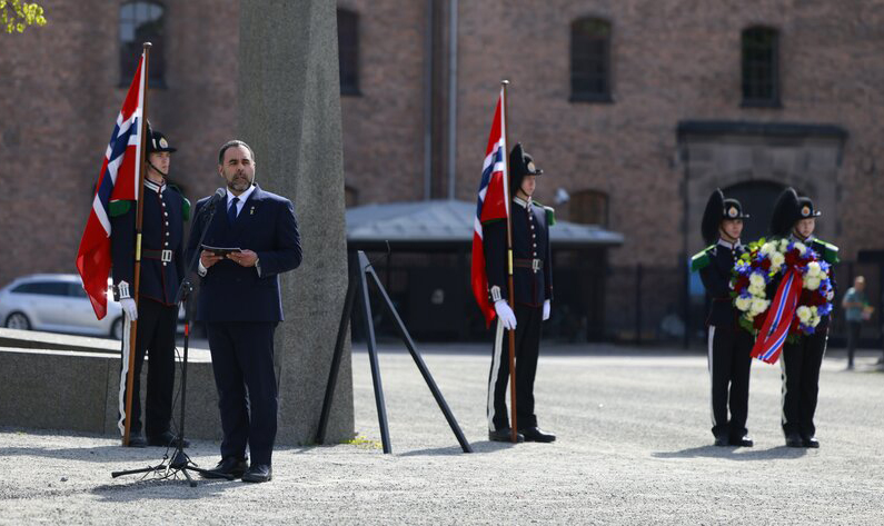 Stortingspresident Masud Gharahkhani holder tale ved veteranmonumentet på Akershus festning. På hver side av seg står to gardister med det norske flagget, To andre gardister i bakgrunnen holder kransen.
