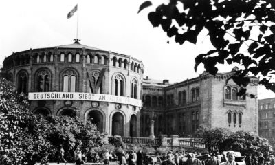 Stortingsbygningen under andre verdenskrig, med tysk propagandaplakat og hakekors i flaggstangen. Foto: Stortingsarkivet
